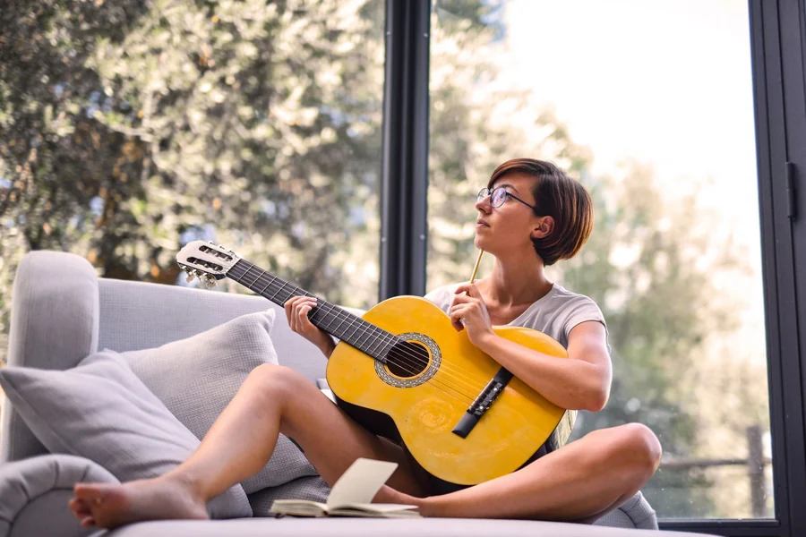 Taylor Swift net worth - woman playing an acoustic guitar at home