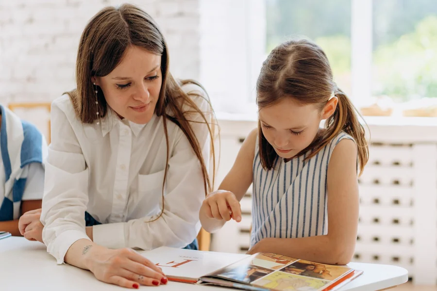 Tina Louise net worth - teacher helping a young girl read a book