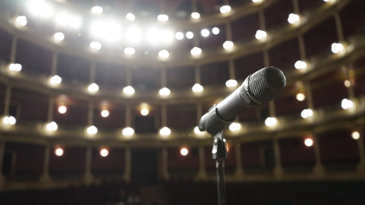 A microphone on a stand on a theatre stage under bright lights