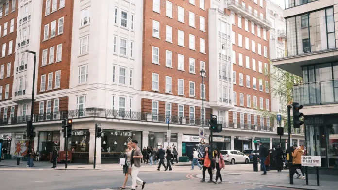 A busy central London street with shops and offices and people crossing the road