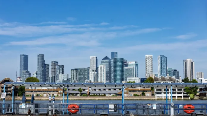 The Canary Wharf skyline in London under a blue sky seen across the water