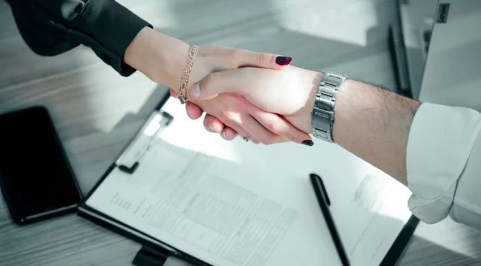 London Business for Sale: How to Finance the Purchase (UK Guide) Two people shaking hands over a signed contract and clipboard to close a business purchase