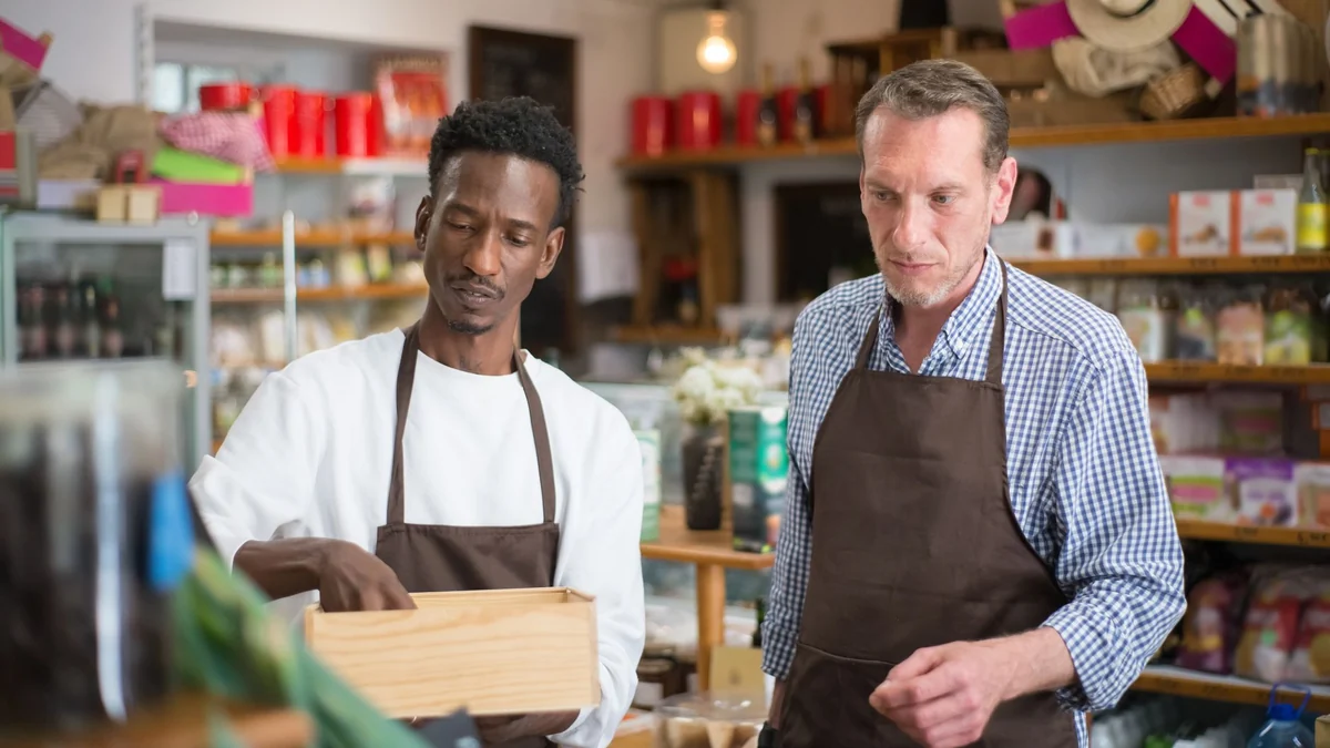 Two shop owners organising stock inside a small independent grocery store