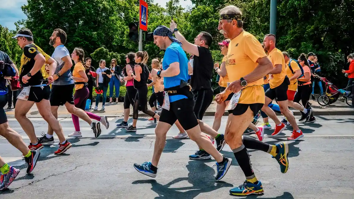 Runners in colourful kit taking part in a marathon on a tree-lined road